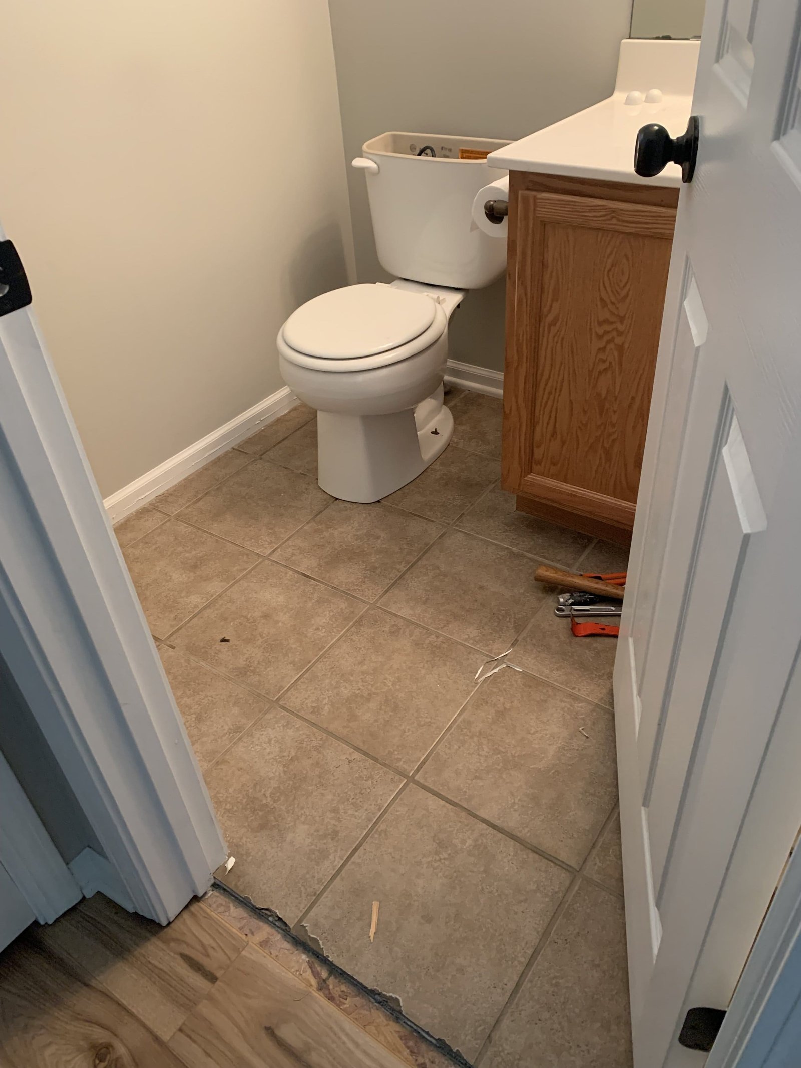Half-bath before — old cracked tile floor